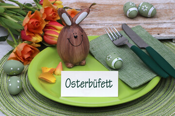 Gedeckter Ostertisch mit Osterdekoration und eine Tischkarte mit der Beschriftung Osterbüfett.