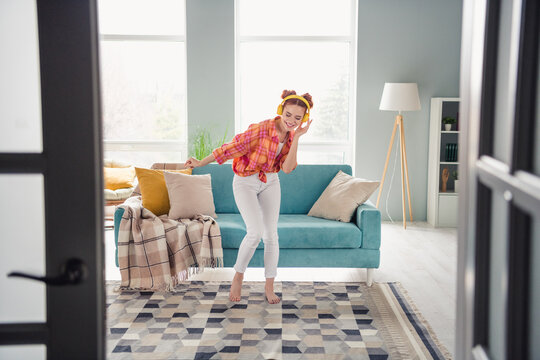 Full size photo of carefree cheerful girl hand touch headphones dancing chilling free time flat indoors