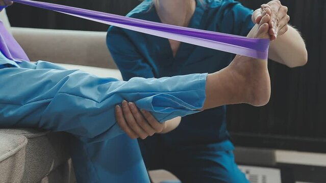 Asian female physiotherapist helping senior older woman stretching hamstring, Rehabilitation physiotherapy, elderly. Causes knee pain, swelling, redness, stiffness in knee, clunking noise in knee.