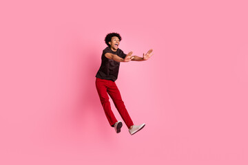 Fototapeta na wymiar Full length body photo funky young guy chevelure hair jumping pushing invisible things in front him isolated on pink color background
