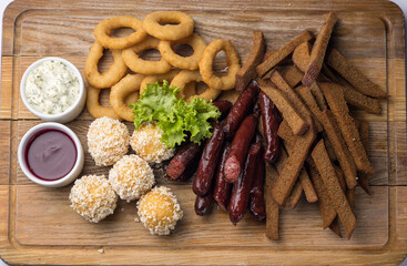 Snacks with sausages, cheese and crackers on a wooden board