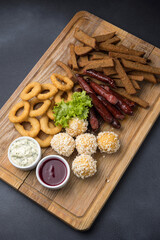 Snacks with sausages, cheese and crackers on a wooden board