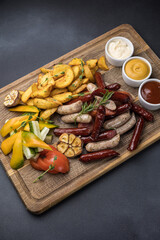 Snacks with sausages, cheese and crackers on a wooden board