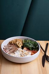 Bowl with rice, veal and vegetables on cafe table. Balanced nutrition concept.