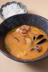 Tom yum soup and rice on a gray background angle view