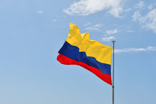 Bandera de Colombia sobre fondo de cielo azul despejado.