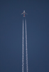 High Altitude Passenger Airliner with Contrails in Deep Blue Sky