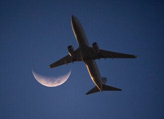 Low-Altitude Commercial Airliner and Crescent Moon at Sunset