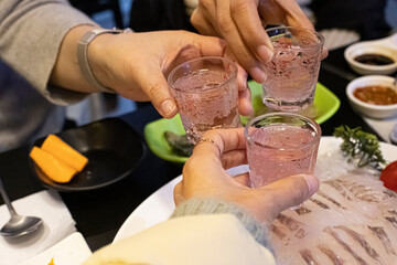 three people who drink and drink traditional Korean liquor soju.