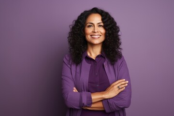 Portrait of a smiling businesswoman with crossed arms against purple background