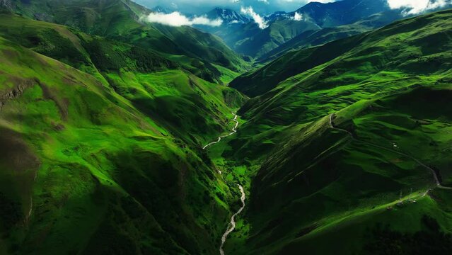 Serpentine river meandering through a vibrant green mountainous landscape with dramatic lighting