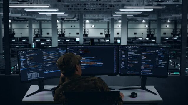 Back View Of Bored Asian Military Write Code With Multiple Computer Screens In Data Center