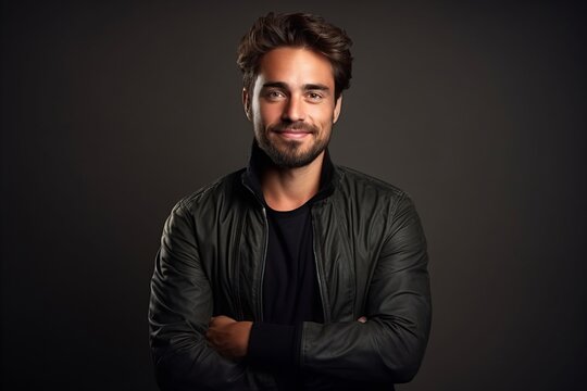 Portrait of a handsome young man in a leather jacket on a dark background.