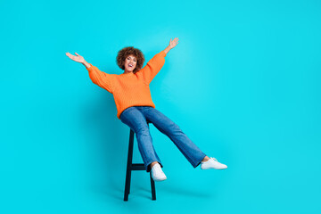 Full size photo of nice carefree girl sit stool raise hands empty space isolated on teal color background