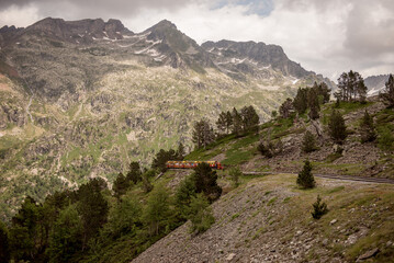 a small tourist train high in the mountains. Train d'Artouste in the Pyrenees mountains. a tourist route high in the mountains. railway in the highlands.	