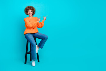 Full size portrait of nice positive girl sit chair direct fingers empty space information isolated on aquamarine color background