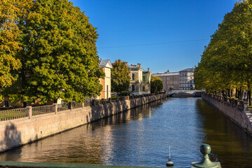 Naklejka premium A picturesque view of the canal, river in the historical town, calm canal with historic houses and green trees under blue sky