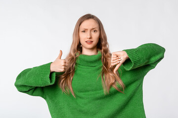 Good or bad. Confused blonde woman shows thumbs up and thumbs down, like and dislike gesture,...