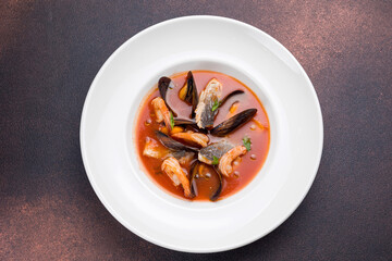 Seafood soup with salmon and mussels in a white plate