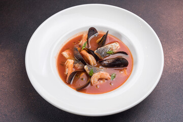 Seafood soup with salmon and mussels in a white plate