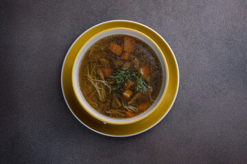 Soup with meat and vegetables in a pot on a dark background
