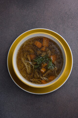 Soup with meat and vegetables in a pot on a dark background
