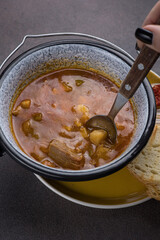 Soup with meat and vegetables in a pot on a dark background