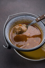 Soup with meat and vegetables in a pot on a dark background