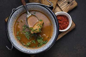 Soup with meat and vegetables in a pot on a dark background