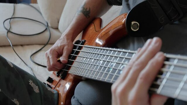 The musician plays a six-string bass guitar