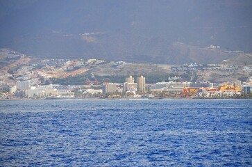 View on resorts and beaches of South coast of Tenerife island during sail boat trip along coastline, Canary islands, Spain in winter