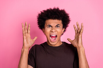 Photo of angry young funny man arms up wearing brown t shirt conflict emotions aggressive grimace...