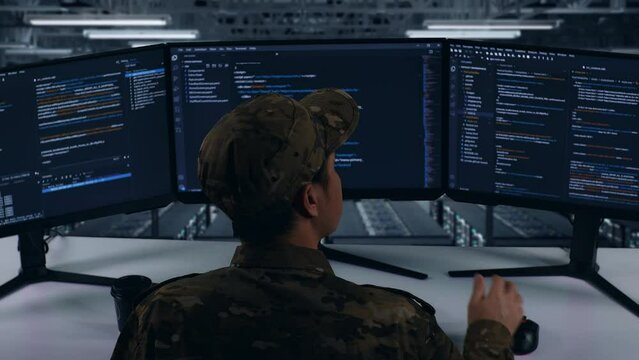 Back View Of Asian Military Thinking About Something While Write Code With Multiple Computer Screens In Data Center
