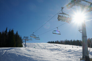 Wyciąg narciarski, kanapa, kolej linowa w ośrodku narciarskim w górach. śnieg, zima, słońce. Pod światło.