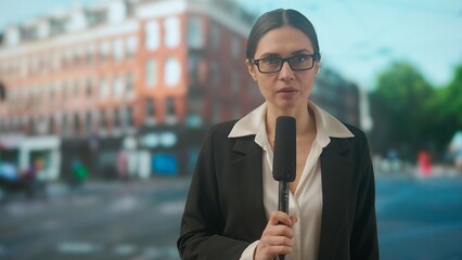 Female presenter reporting on air outside. Woman news host journalist talking with studio, wearing...