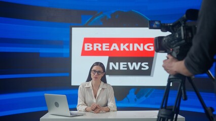 Female presenter in the studio. Woman news host sits at desk presenting daily events.