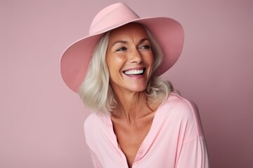 Portrait of a happy senior woman in pink hat over pink background