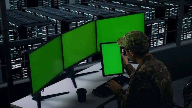 Side View Of Asian Military Working With Tablet And Multiple Computer Monitor With Mock Up Green Screen In Data Center