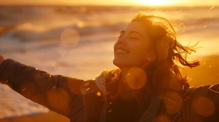 Portrait of calm, happy, smiling free woman with open arms and closed eyes enjoying a beautiful moment of life on the seashore at sunset