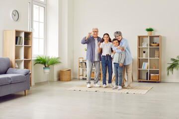 Full length portrait of happy jouful smiling senior grandparents having fun with their grandchildren brother and sister standing in the living room at home. Family leisure concept.