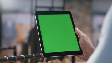 Man hands holding greenscreen tablet collect production data at boutique closeup