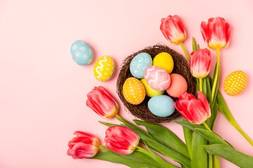 Fototapeta na wymiar Easter eggs with a bouquet of tulips on a bright background. Easter celebration concept. Colorful easter handmade decorated Easter eggs. Place for text. Copy space.