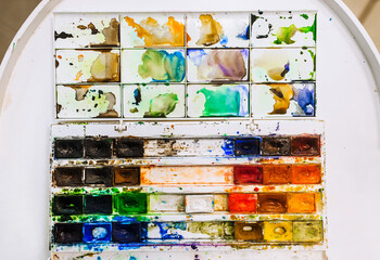 Background, texture of watercolor colored paints in disarray, in a dirty box on a white table....
