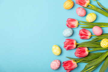 Easter eggs with a bouquet of tulips on a bright background. Easter celebration concept. Colorful easter handmade decorated Easter eggs. Place for text. Copy space.