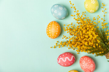 Easter eggs with mimosa flowers on a bright background. Easter celebration concept. Colorful easter handmade decorated Easter eggs. Place for text. Copy space.