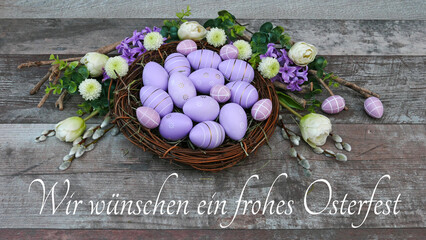 Dekoratives Nest mit lila Ostereiern und dem Gruß wir wünschen ein frohes Osterfest.