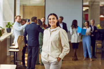 Portrait of a happy smiling confident young business woman looking at the camera with a team of...