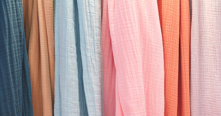 Multi-colored textile fabrics hang in a market or store as an abstract background