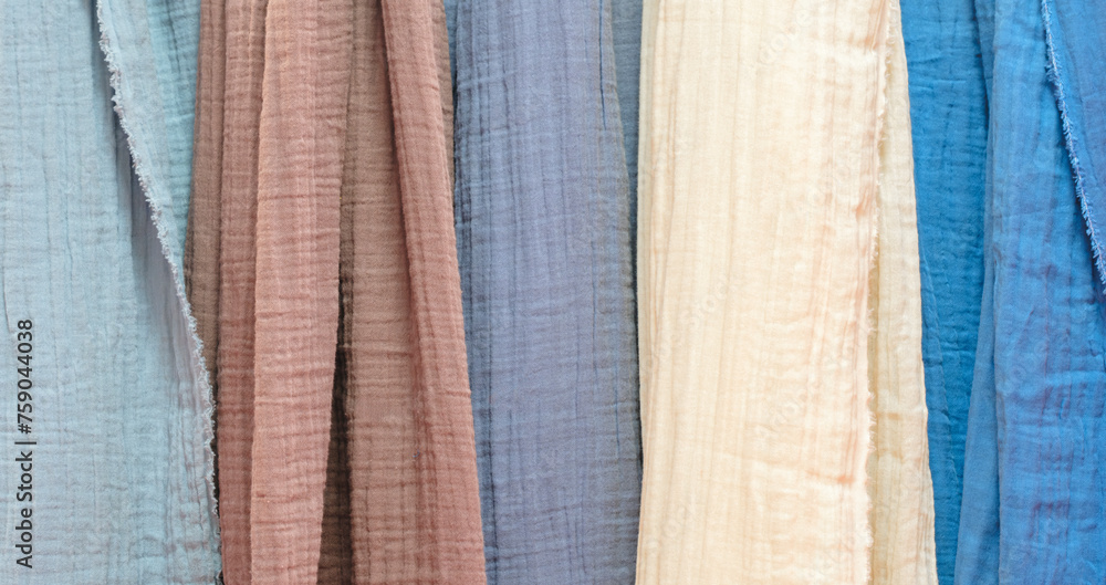 Poster multi-colored textile fabrics hang in a market or store as an abstract background