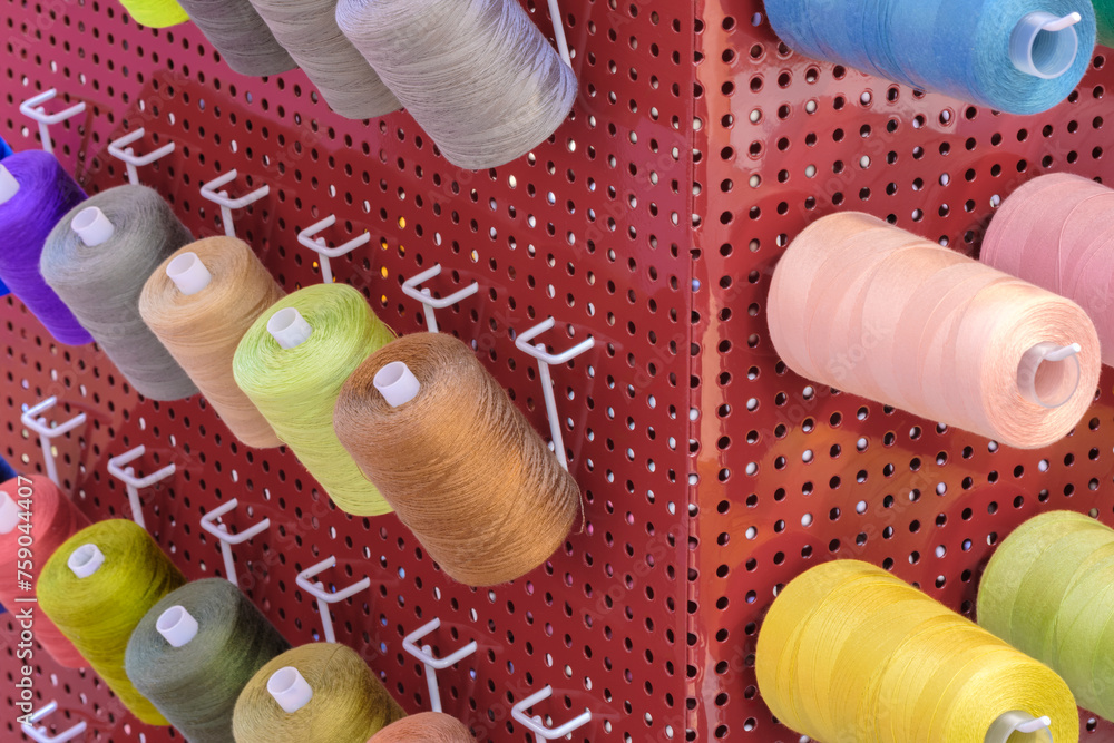 Aufkleber a row of colorful spools of thread are displayed in a store. the spools are arranged in a rainbow pa